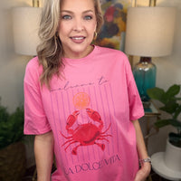 Woman wearing a pink t-shirt with a crab design in a home setting