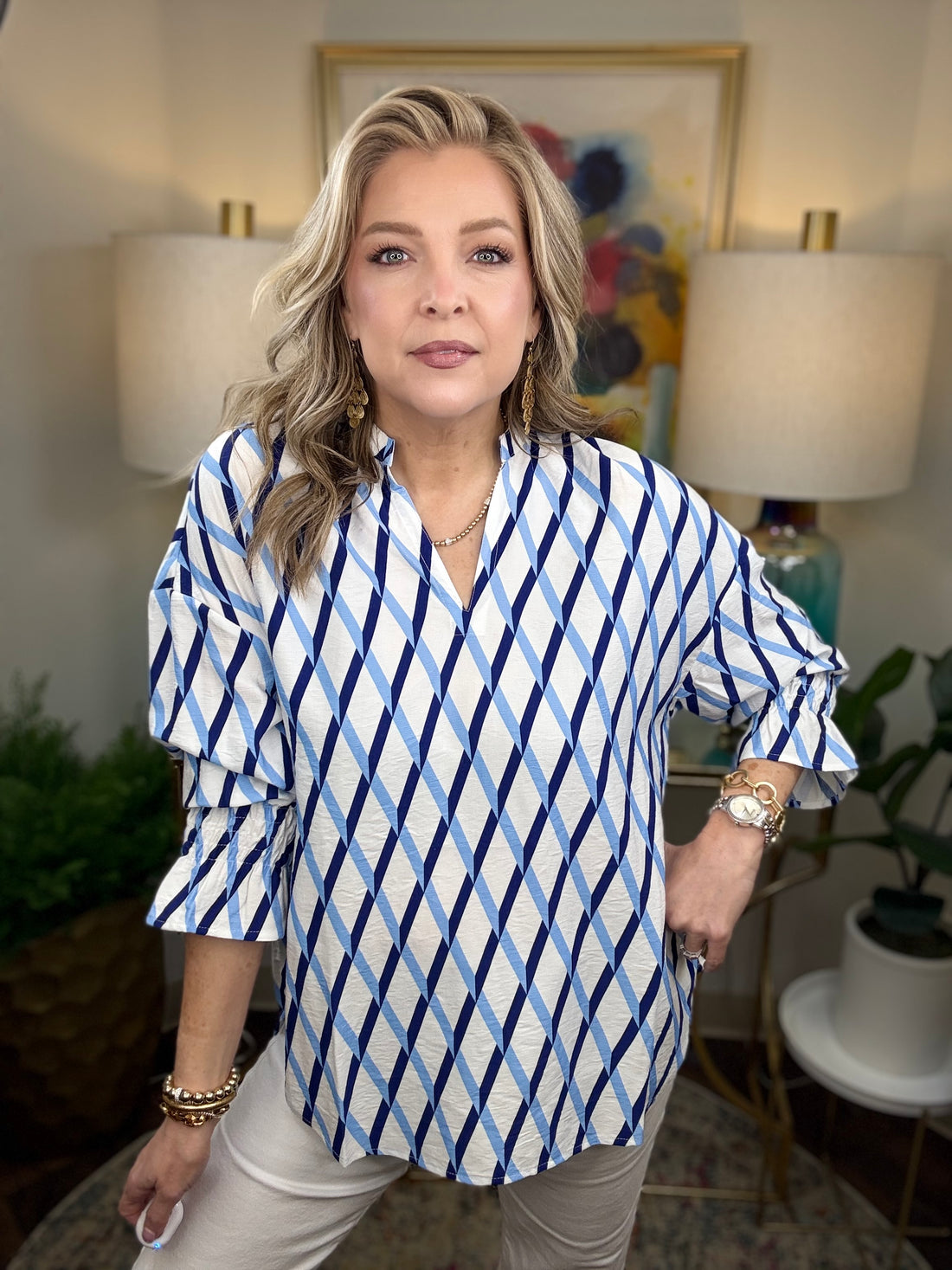 Woman wearing a white blouse with dark and light blue criss cross patterns