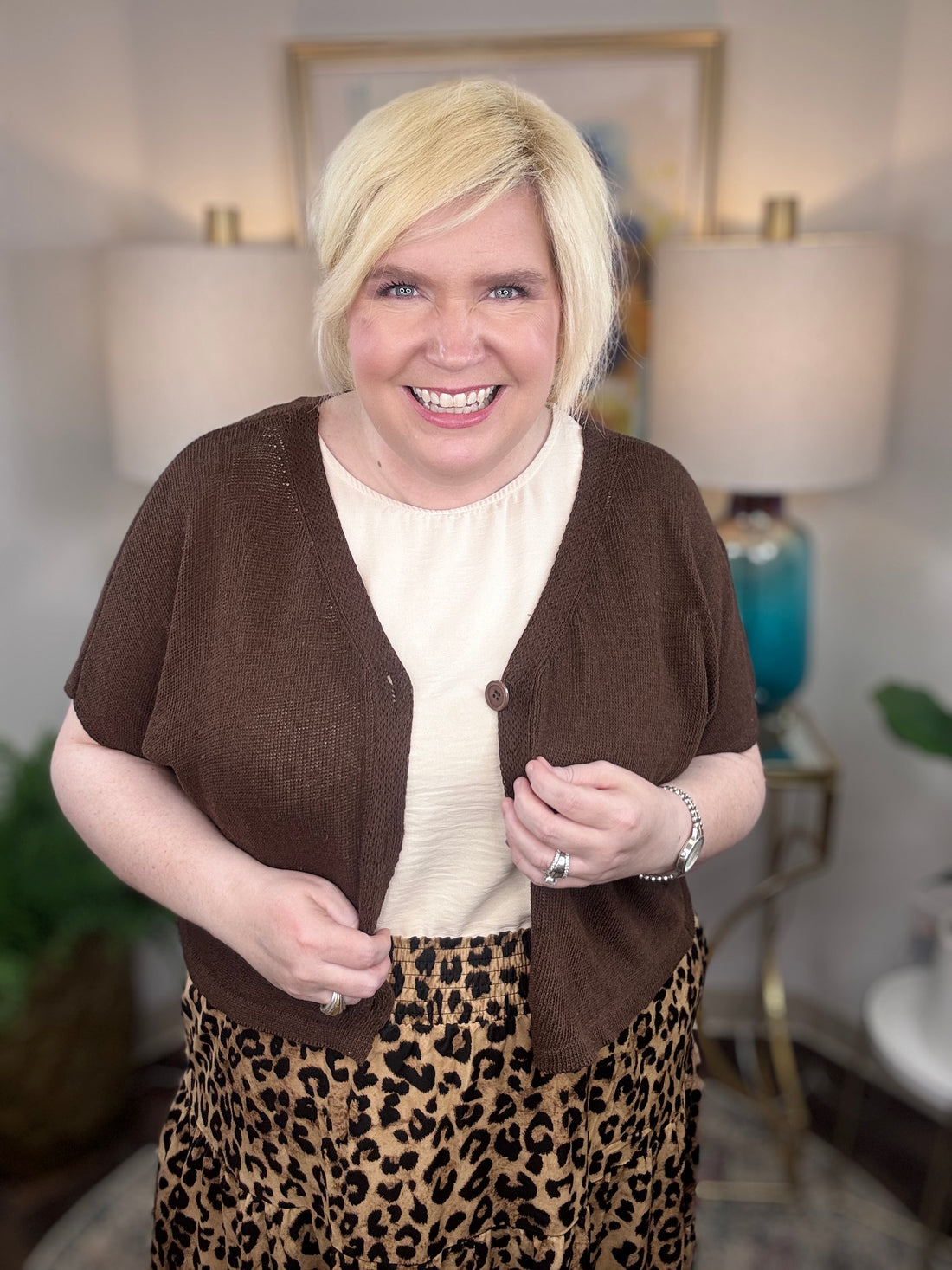 Woman wearing a brown cardigan and leopard print skirt indoors.