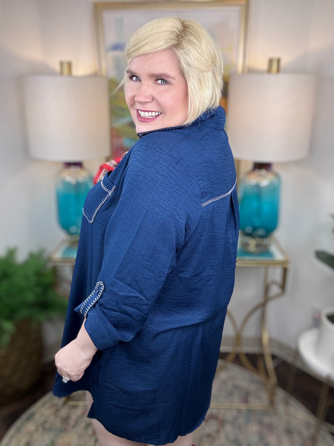 Person wearing a blue jacket in an indoor setting with lamps and decor.