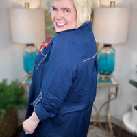 Person wearing a blue jacket in an indoor setting with lamps and decor.