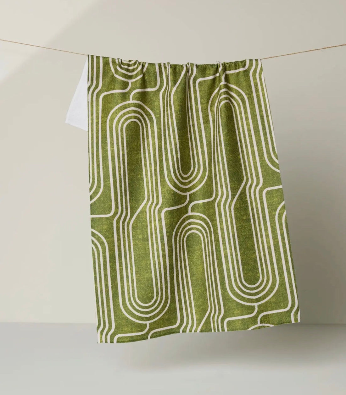 Green tea towel with white geometric pattern on a white background