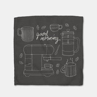 Black towel with white line art of coffee-making equipment and 'good morning' 