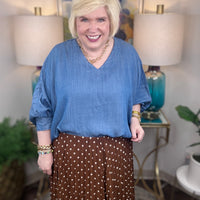 Woman wearing a denim v-neck dolman sleeve blouse