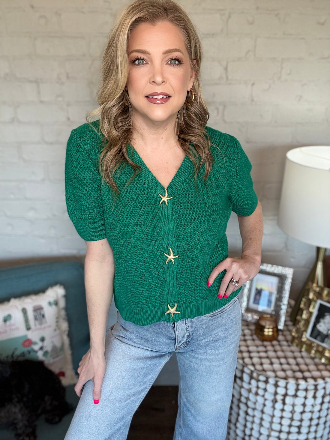 A woman wearing green sweater cardigans with gold starfish buttons.