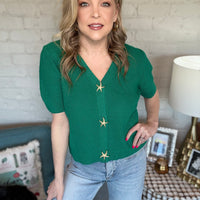 A woman wearing green sweater cardigans with gold starfish buttons.