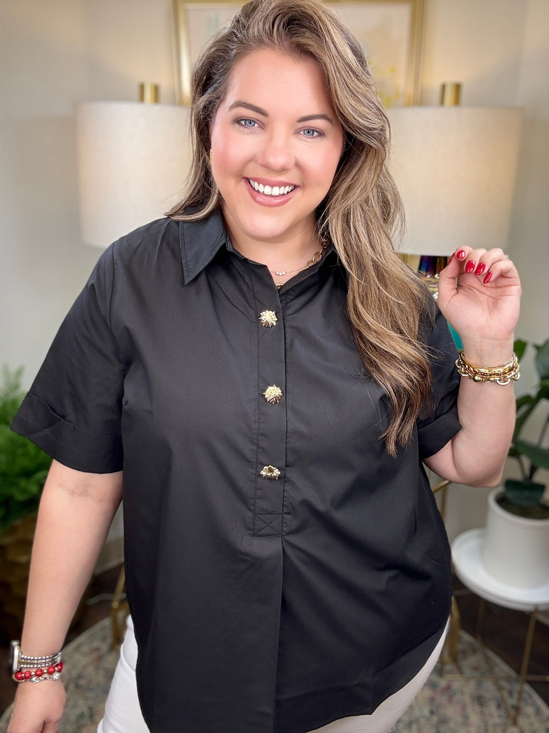 Woman wearing a black blouse with gold buttons