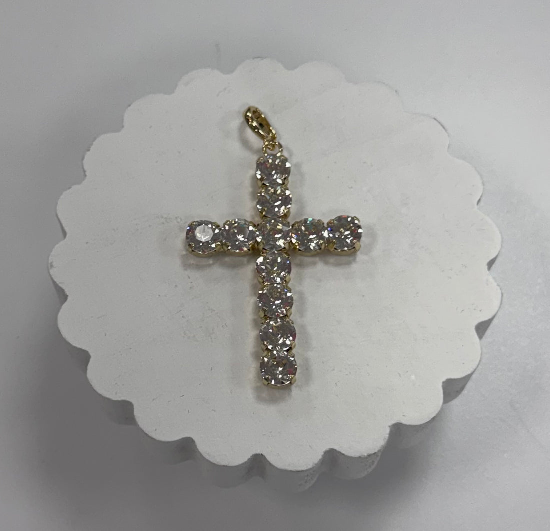 Gold cross pendant with clear stones on a white scalloped card