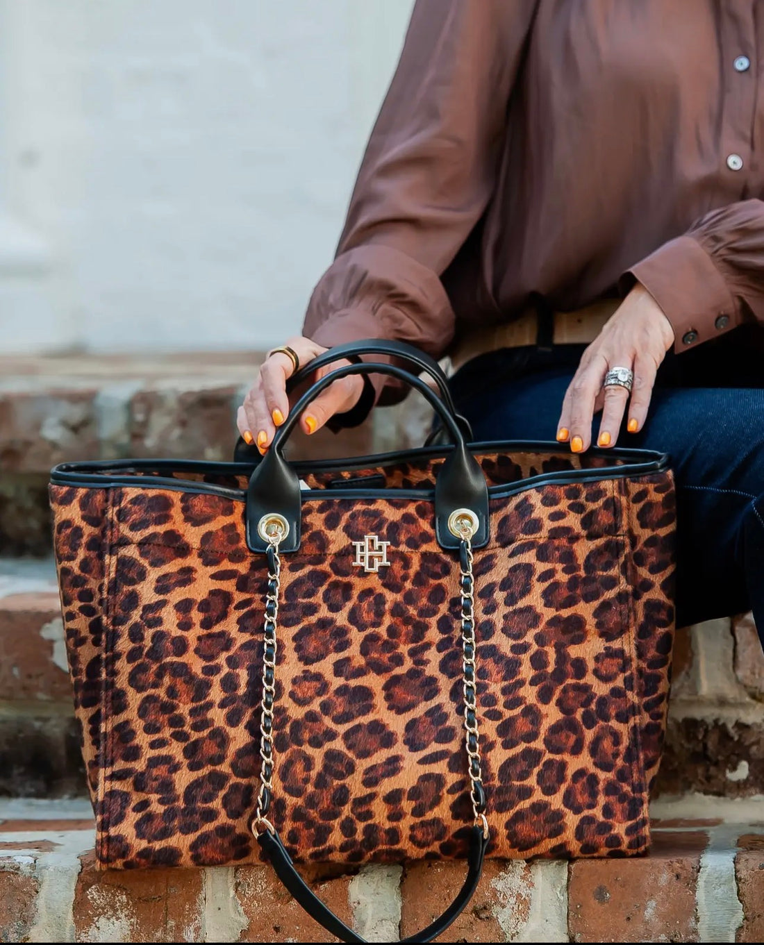 Person holding a leopard print handbag with a blurred background