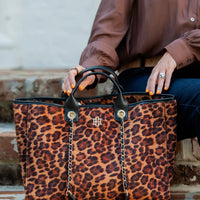 Person holding a leopard print handbag with a blurred background