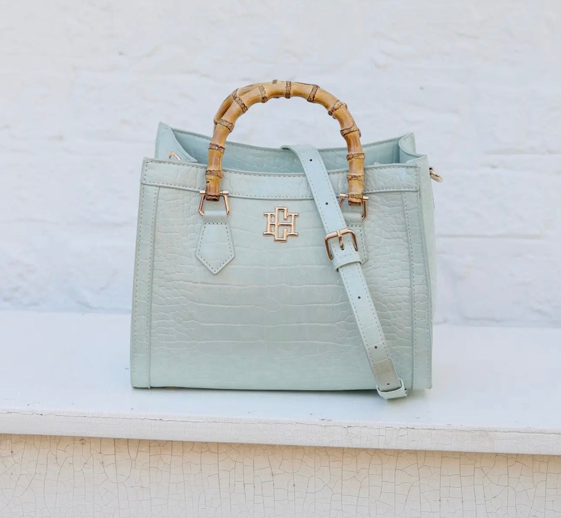 Light blue handbag with bamboo handle on a white background