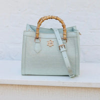 Light blue handbag with bamboo handle on a white background
