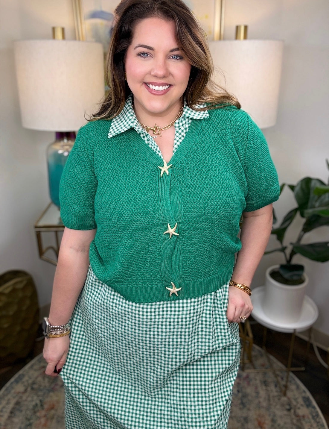 A woman wearing green sweater cardigans with gold starfish buttons.