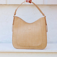 Beige handbag with a brand logo held by a hand against a light background