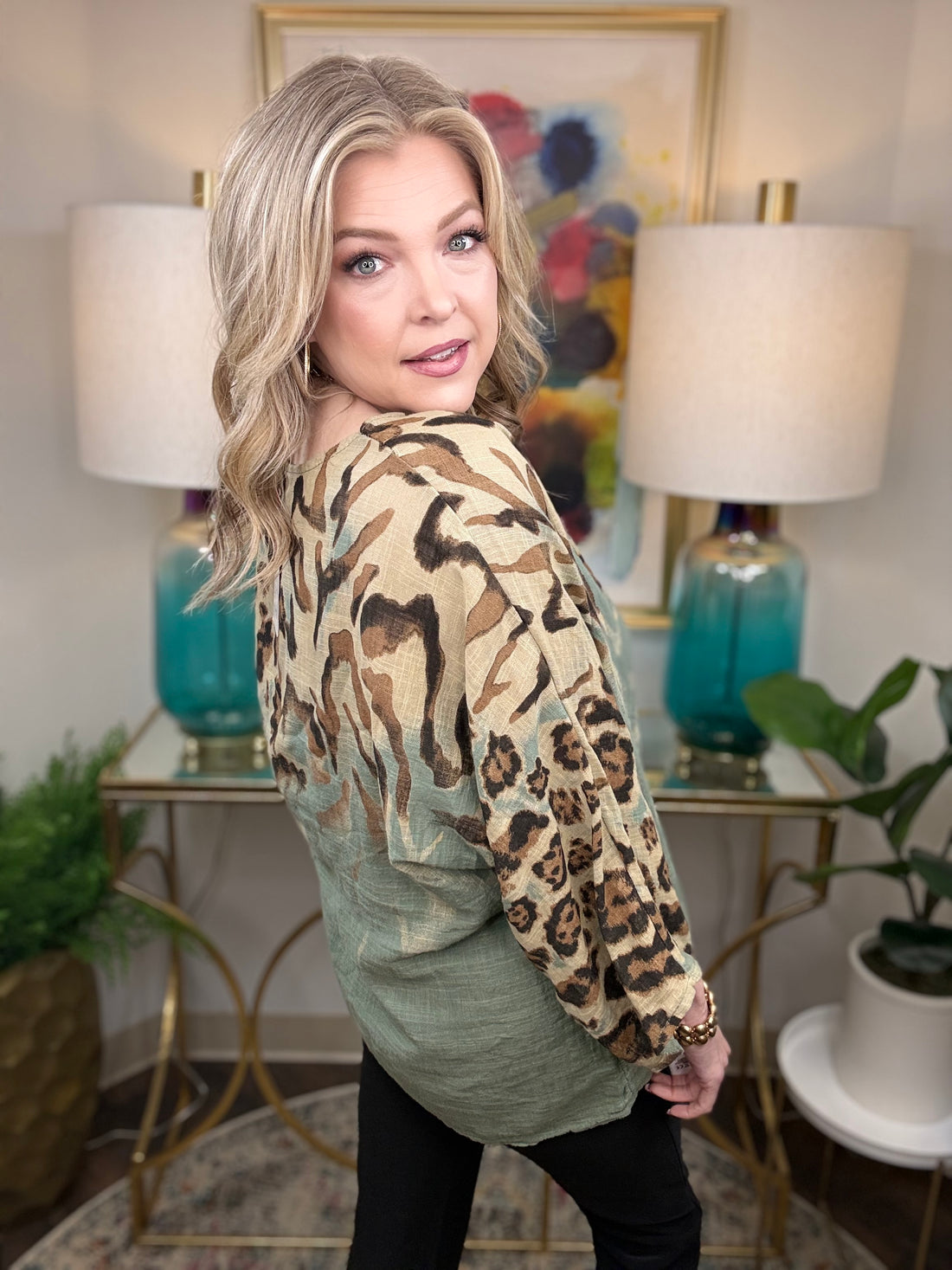 Woman wearing a patterned jacket in a room with lamps and artwork.