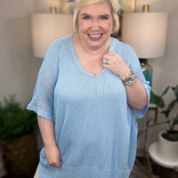 Woman wearing a light blue short-sleeved tunic sweater.
