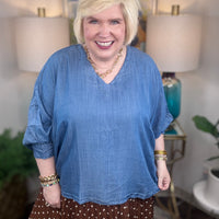 Woman wearing a denim v-neck dolman sleeve blouse