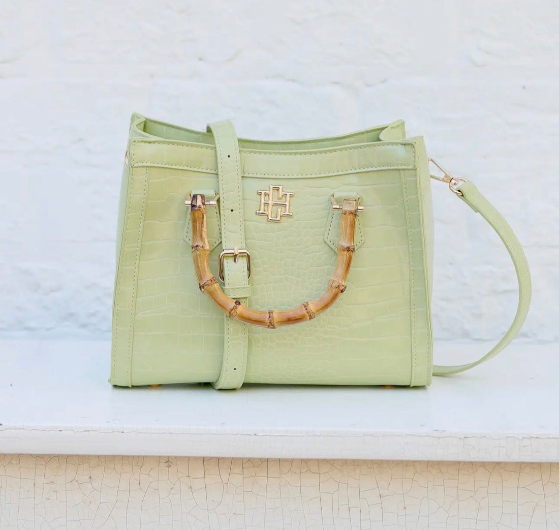 Light green handbag with bamboo handle on a white surface