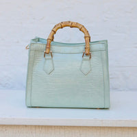 Light blue handbag with bamboo handles on a light background