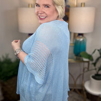 Woman wearing a light blue short-sleeved tunic sweater.