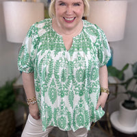 Woman wearing a green and white blouse. 