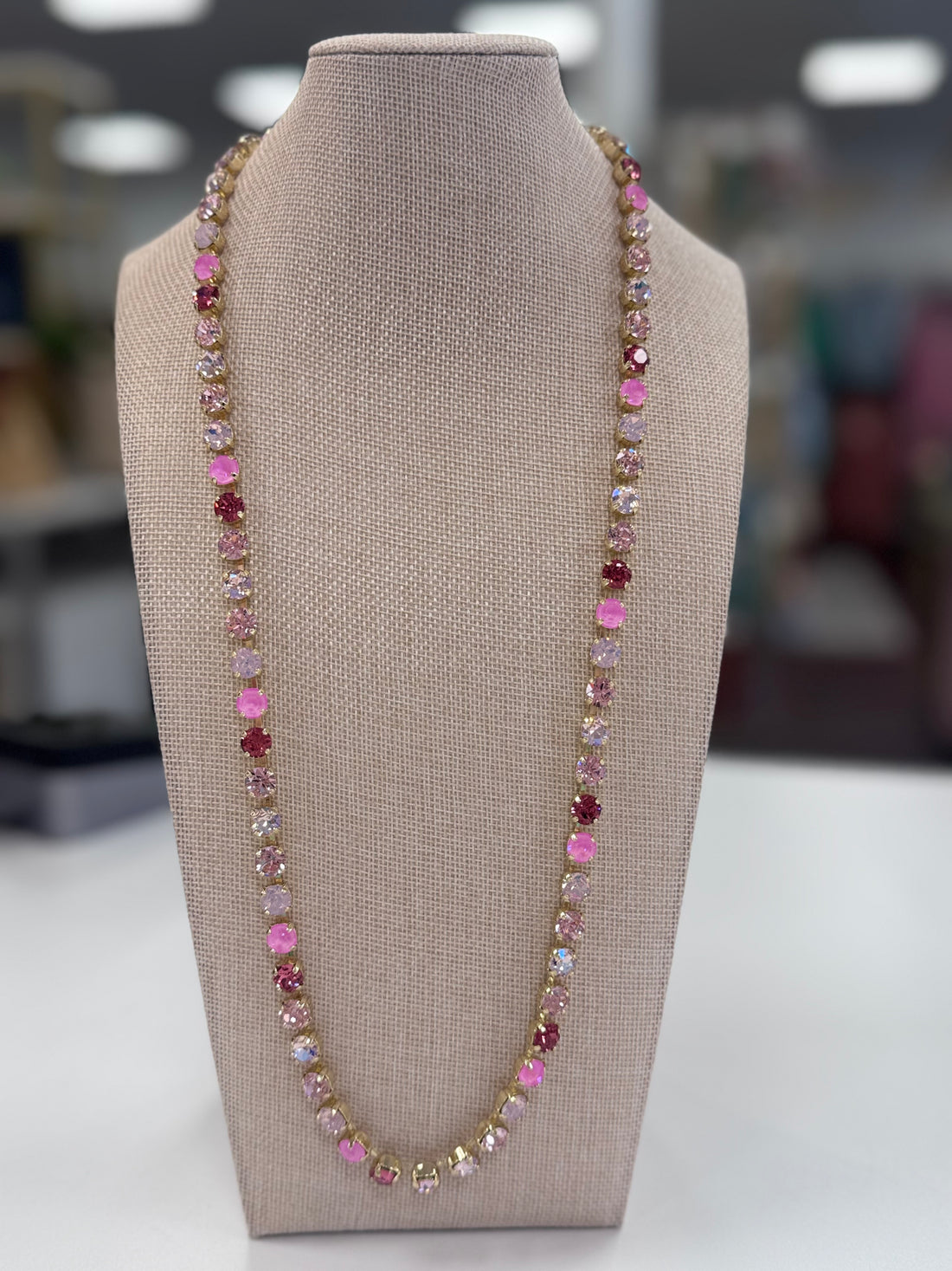 Necklace with pink and multicolored stones on a gray bust