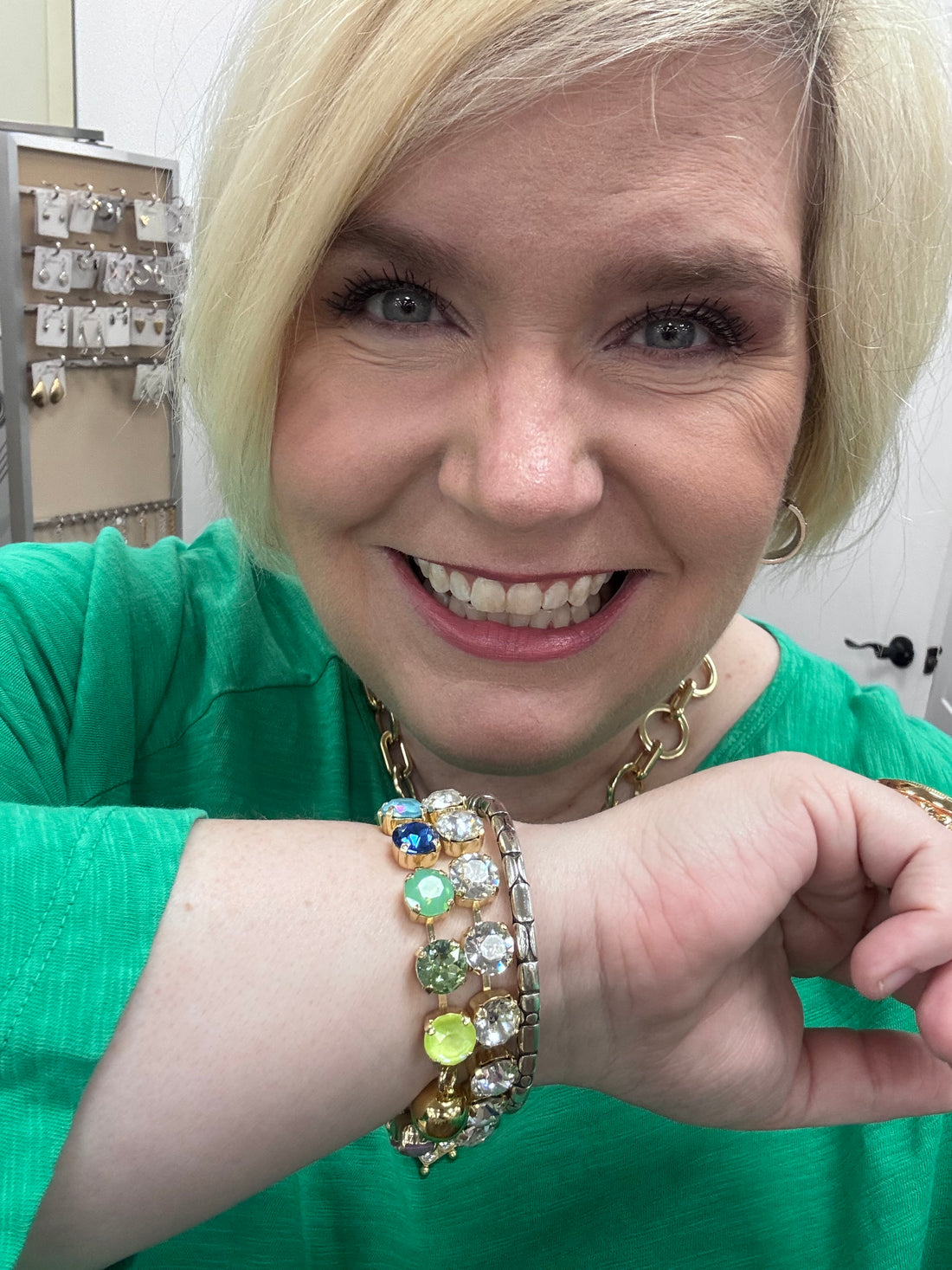 Woman wearing multiple bracelets with colorful gemstones, smiling.