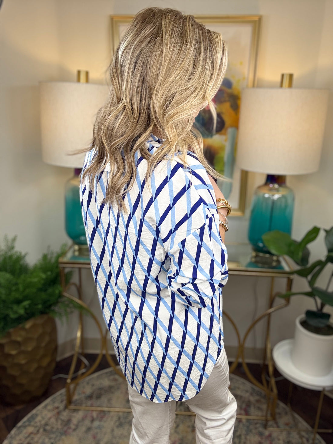 Woman wearing a white blouse with dark and light blue criss cross patterns