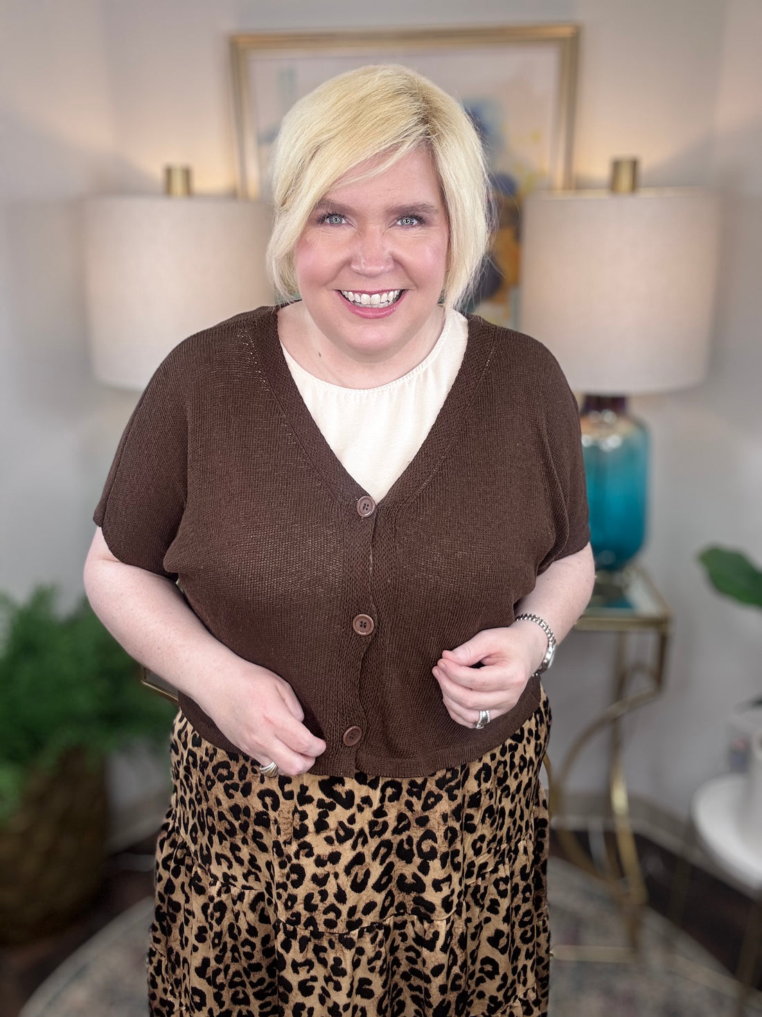 Woman wearing a brown cardigan and leopard print skirt indoors.