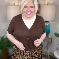Woman wearing a brown cardigan and leopard print skirt indoors.
