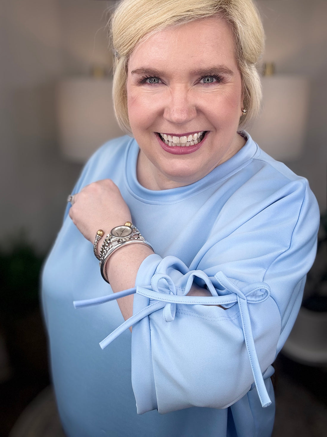 Woman wearing a baby blue matching set with bows tied on the sleeves.
