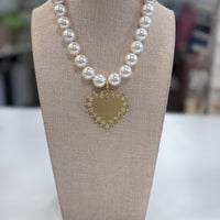 Pearl necklace with a heart-shaped pendant on a gray bust