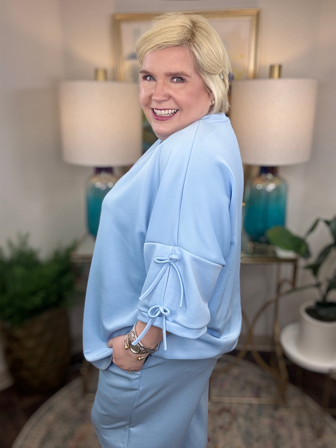 Woman wearing a baby blue matching set with bows tied on the sleeves.