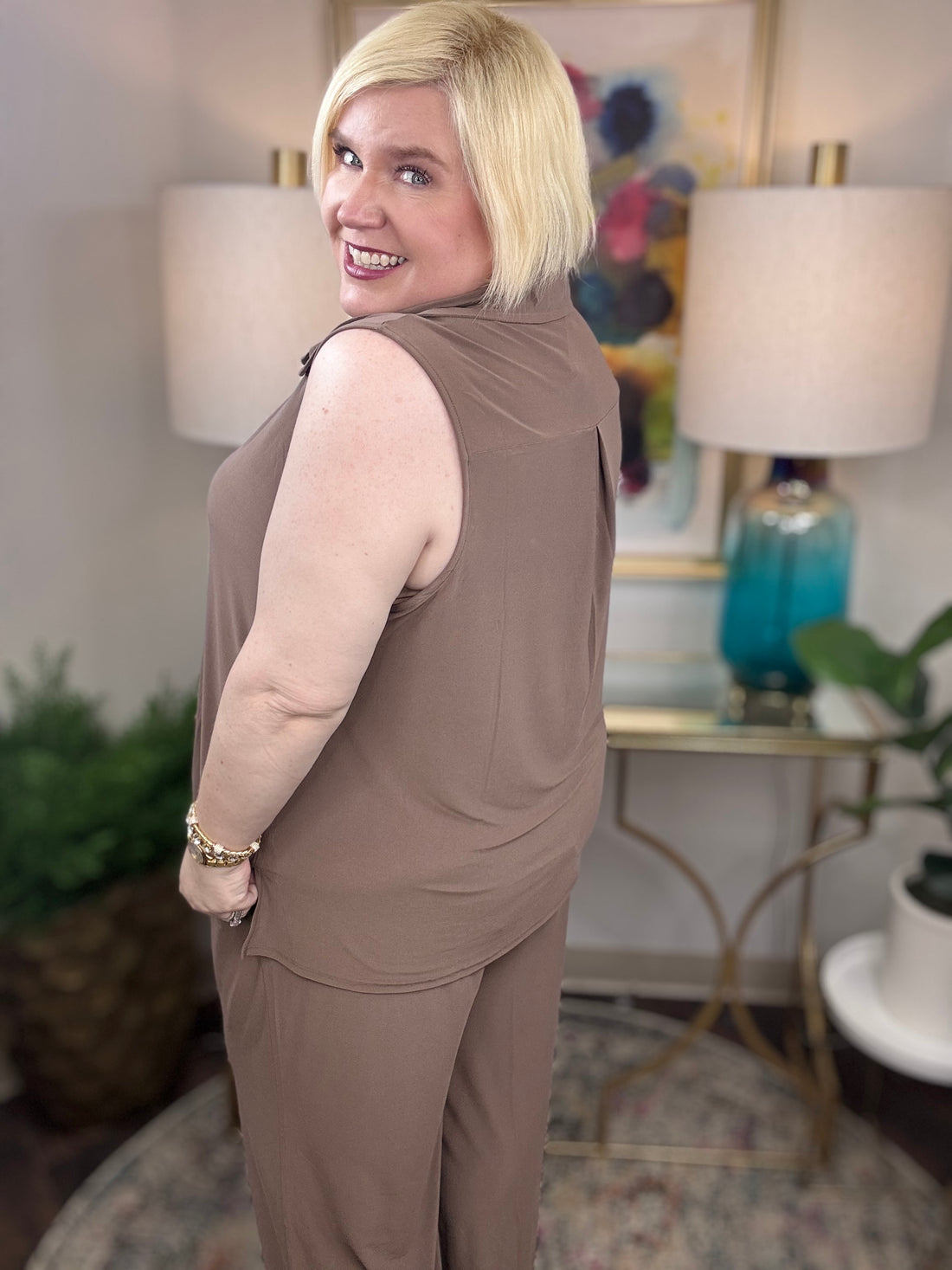 Woman wearing a mocha brown sleeveless top and pants with gold buttons