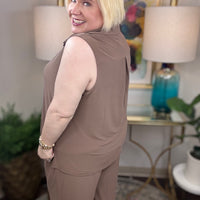 Woman wearing a mocha brown sleeveless top and pants with gold buttons