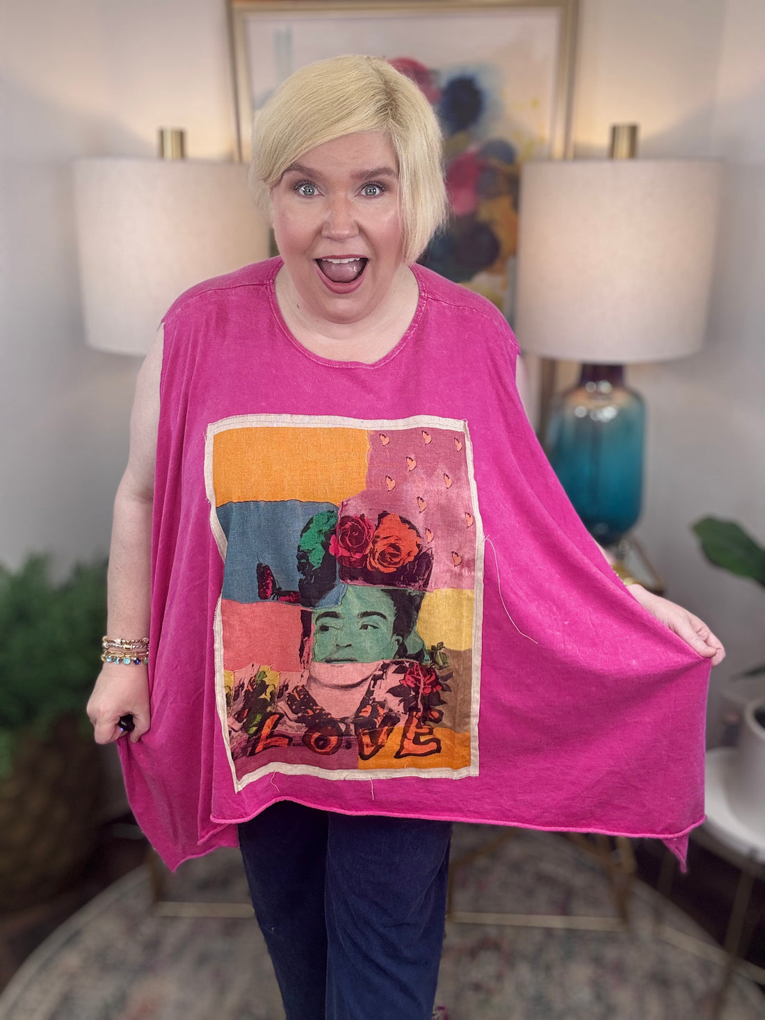 woman wearing a sleeveless bright pink top with a large colorful Frida Kahlo graphic print on the front