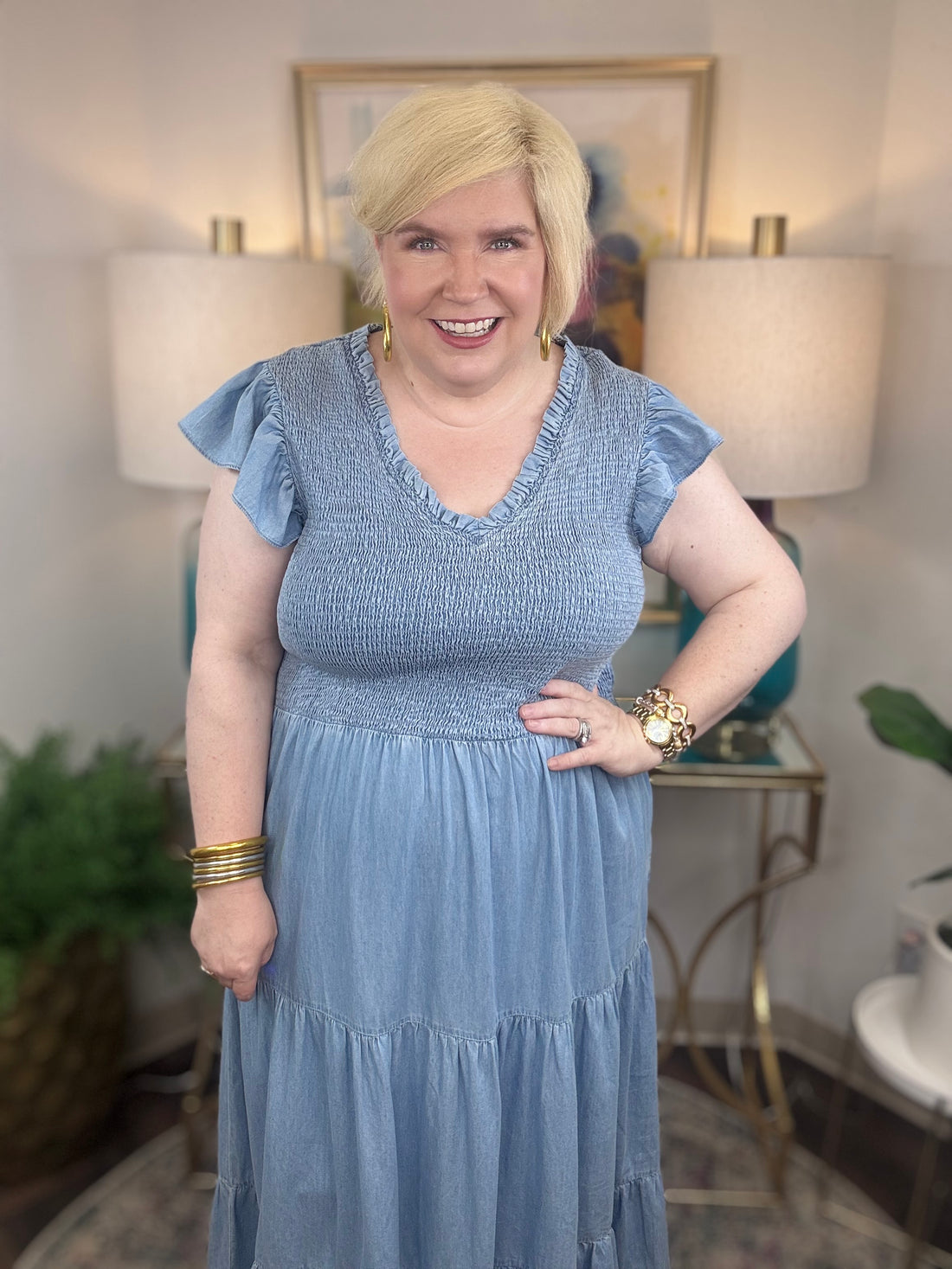A woman wearing a light blue denim maxi dress with a smocked bodice and short ruffled sleeves