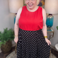 Woman wearing a red top and black polka dot skirt