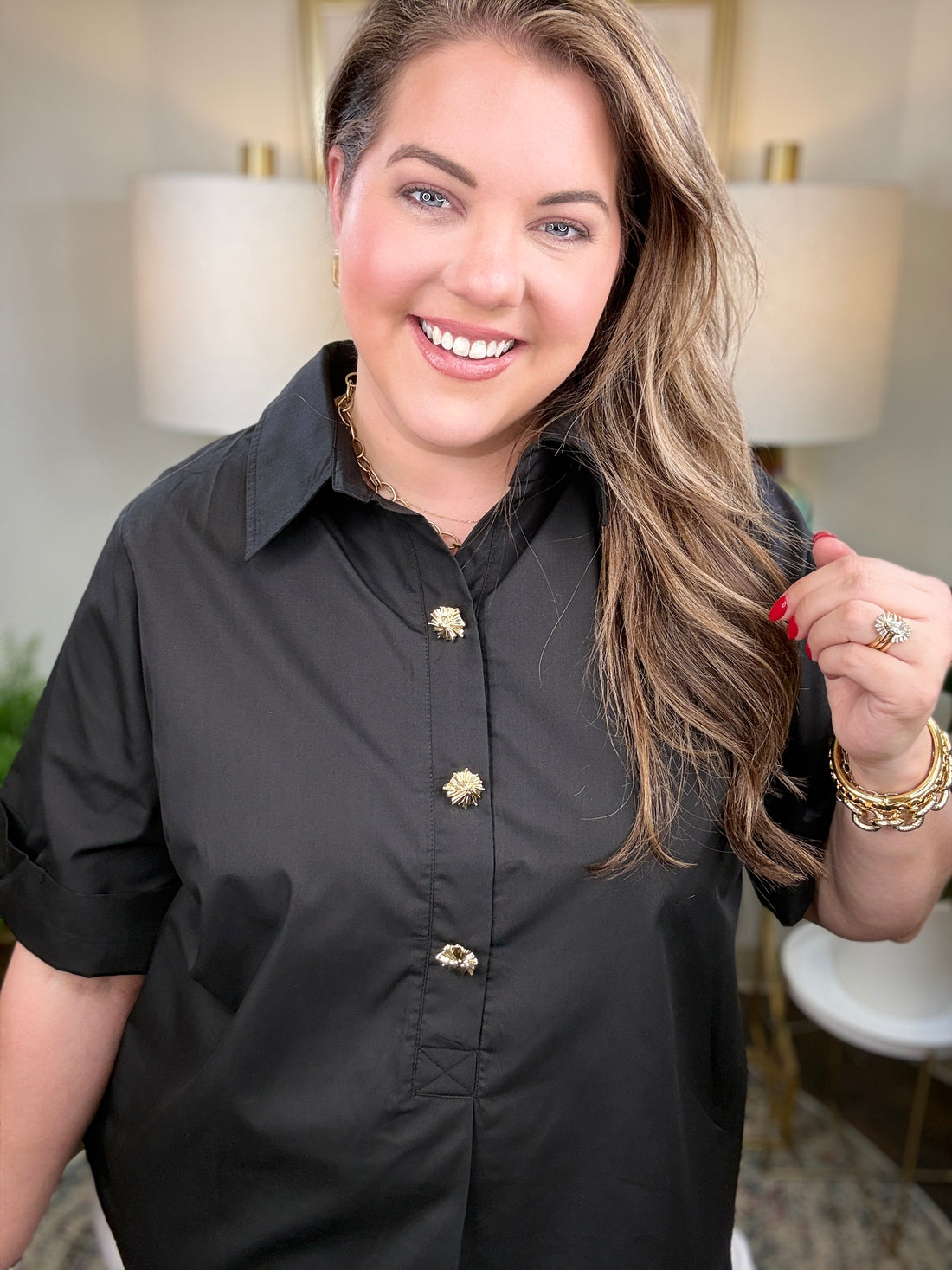 Woman wearing a black blouse with gold buttons