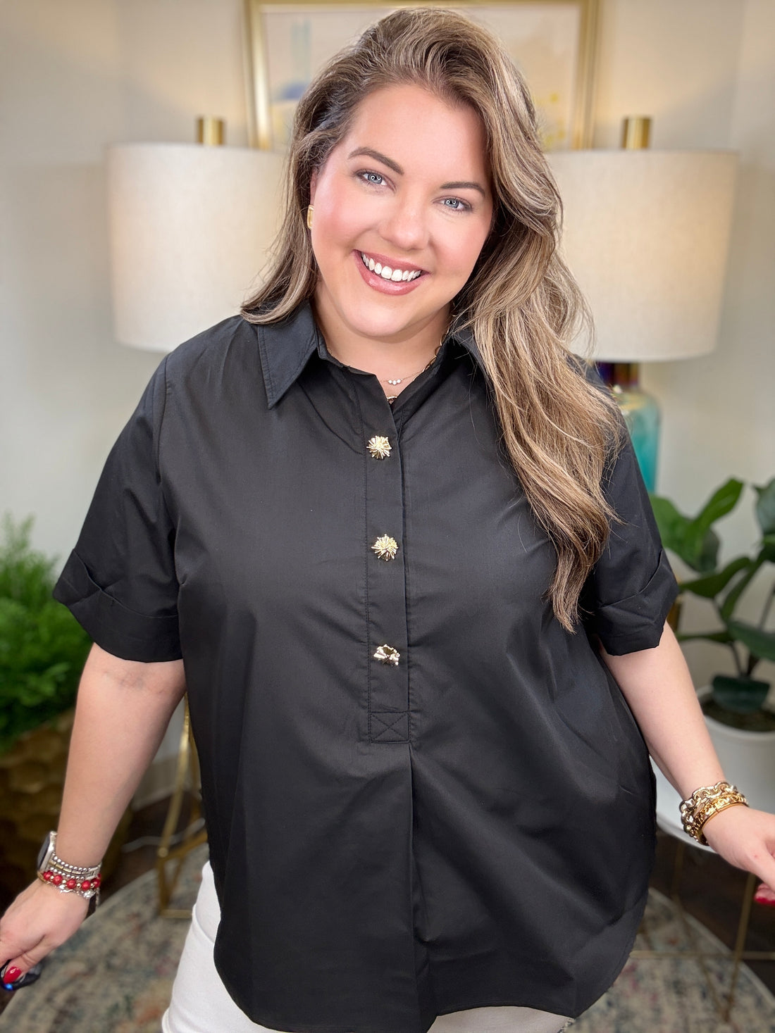 Woman wearing a black blouse with gold buttons