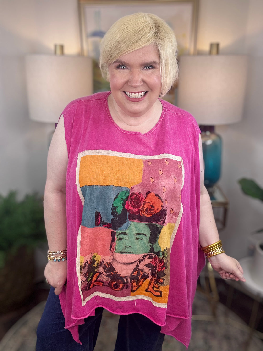 woman wearing a sleeveless bright pink top with a large colorful Frida Kahlo graphic print on the front