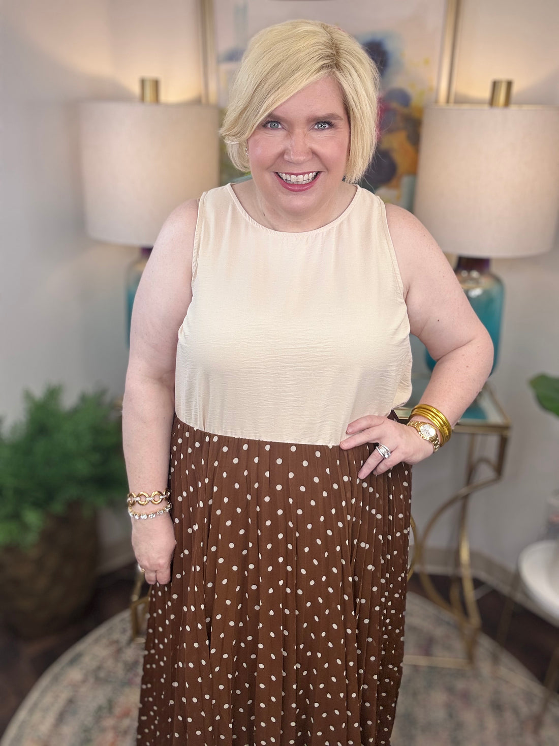 Woman wearing a beige top and brown polka dot skirt indoors.