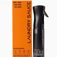 Black spray bottle and orange box of Laundry Sauce on a white background