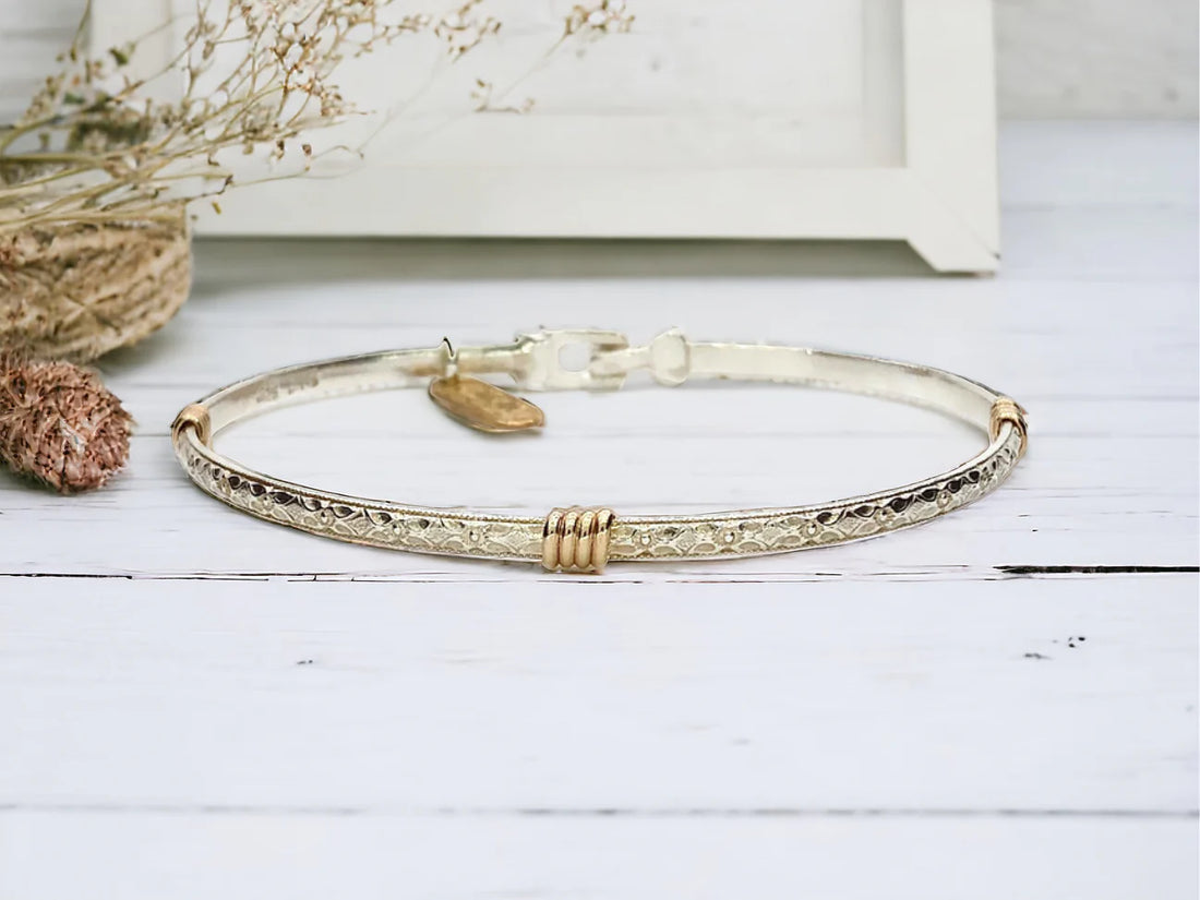 Silver band bracelet with gold wrap detail.