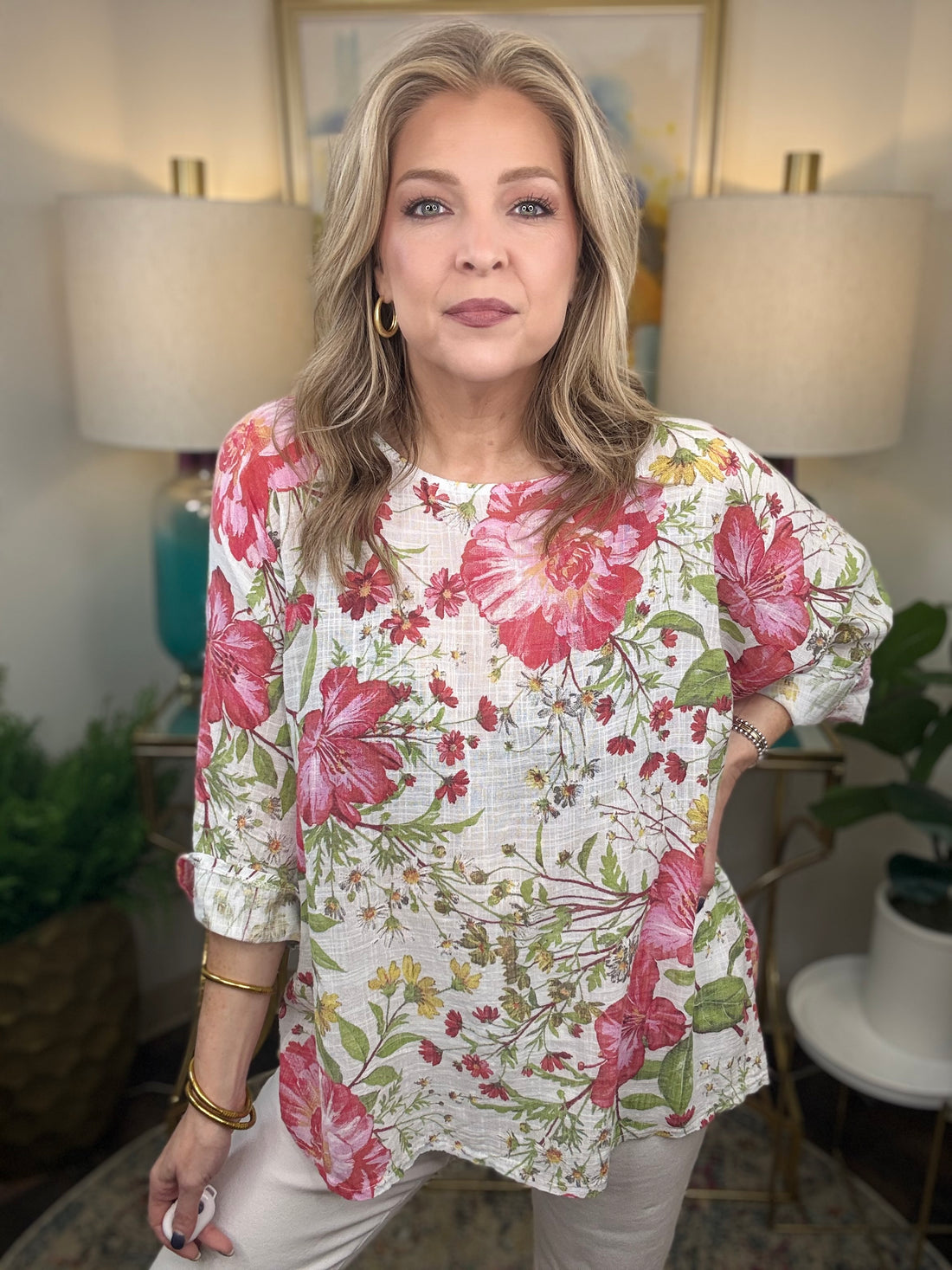 Woman wearing a floral blouse in a room with lamps and plants