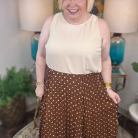 Woman wearing a beige top and brown polka dot skirt