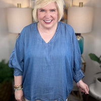 Woman wearing a denim v-neck dolman sleeve blouse