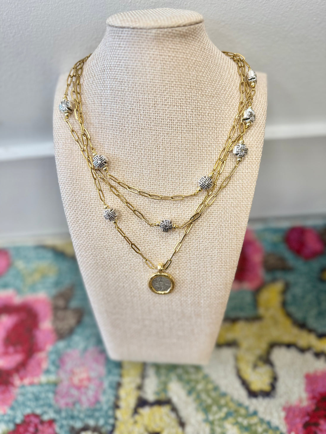 Stacked mixed metal necklace with a focal coin and silver cross accents