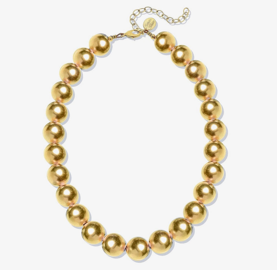 A gold-toned beaded necklace with large, glossy spherical beads and a matching chain extender clasp, displayed on a clean white background.