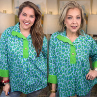 Two women wearing a green and blue patterned blouse with green collars and cuffs.